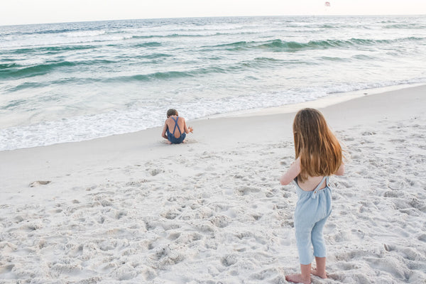 Playing in the sand while wearing our Super soft double gauze overalls in Seafoam and In Ocean.