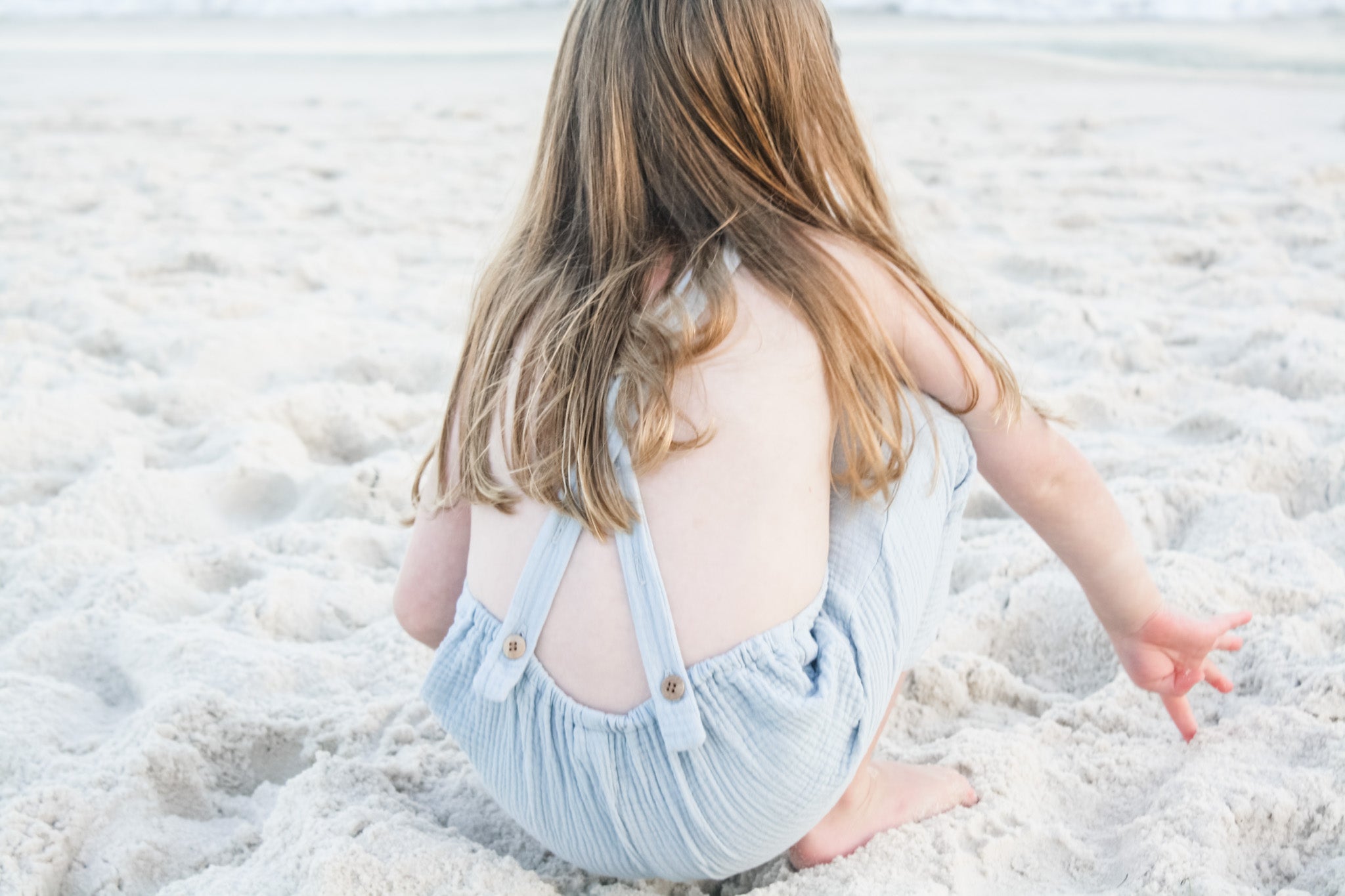 Playing in the sand while wearing our Super soft double gauze overalls in Seafoam.